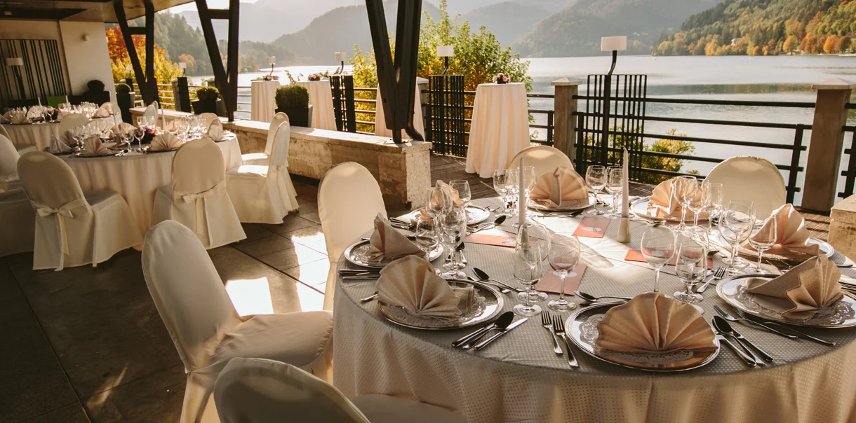 Restavracija s svetlo opremljenimi mizami in stoli s pogledom na blejsko jezero